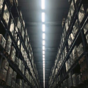 Large warehouse with pallet racking systems, forklifts moving pallets, and efficient storage layout